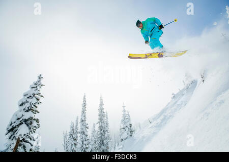 Junger Mann springt von Skipiste Stockfoto