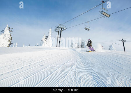 Mid-Adult Woman auf Skipiste unter Seilbahn Stockfoto