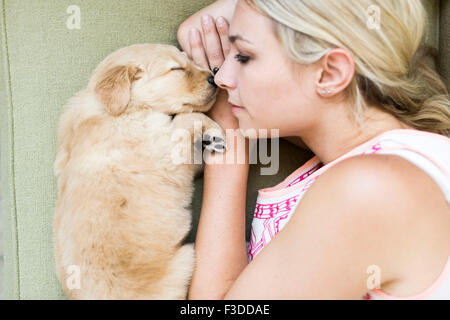 Porträt von Welpen mit Besitzer liegend auf sofa Stockfoto