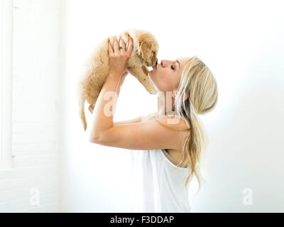 Studioaufnahme des Besitzers küssen Golden Retriever Welpen Stockfoto