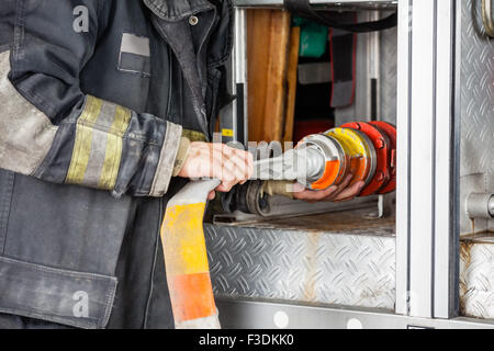 Mittelteil der Feuerwehrmann Schlauch In LKW anpassen Stockfoto