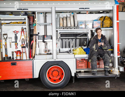 Firewoman Holding Coffee Mug in Lkw Stockfoto