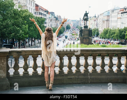 Von hinten gesehen, steht langhaarigen Hippie aussehende Frau Tourist mit ausgestreckten Armen schaut auf St.-Wenzels-Statue o Stockfoto