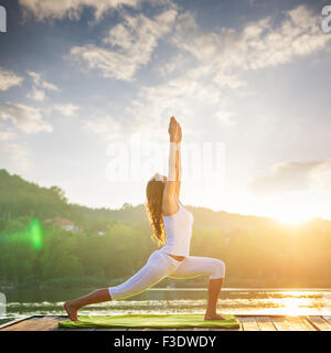 Frau beim Yoga am See - schöne Lichter Stockfoto