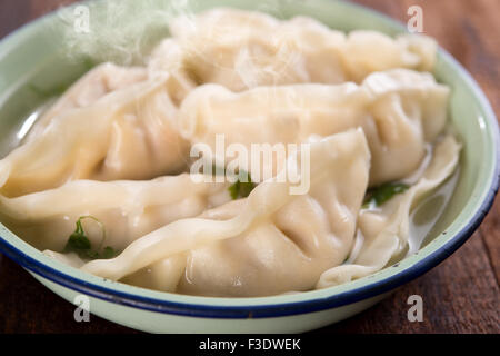 Frische Knödel Suppe auf Teller mit heißen Dämpfe hautnah. Chinese Gourmet auf alten Vintage Holz-Hintergrund. Stockfoto