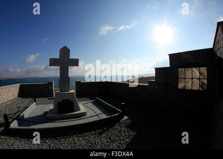 Eine Stein gefertigte Wand legt den Umfang der Gedenkstätte Russo-Kozak. St.Nicholas Inselchen im Hintergrund von Mudros Golf sichtbar. Lemnos Stockfoto