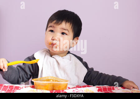 Säuglingsernährung, die sich mit einem Löffel Stockfoto