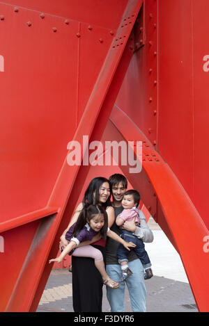 Familie mit zwei Kindern unter Skulptur stehend Stockfoto