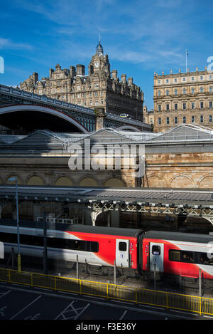 Ein natives Zug sitzen an Waverley Station Edinburgh mit North Bridge und das Balmoral Hotel im Hintergrund. Stockfoto