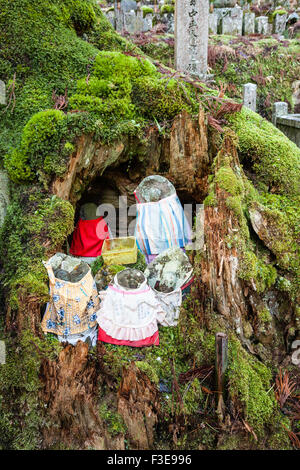 Japan, Koyasan Friedhof, Okunoin. Gruppe von fünf bibbed jizo bosatsu Statuen aus Stein und Kunststoff collection Warenkorb in Ausgehöhlten Cedar Tree Trunk. Stockfoto