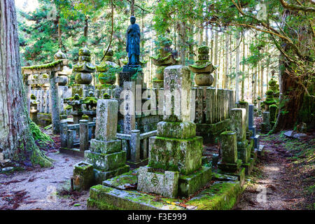 Japan, Koyasan Friedhof, Okunoin. Statue des Priesters auf großen Grabstein, mit torii Tor, Grabsteine und fünf Stein Pagoden im Zedernwald. Stockfoto