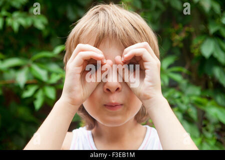 Boy Looking durch Finger wie Ferngläser im freien Stockfoto