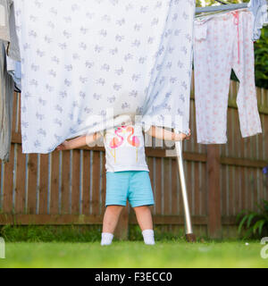 3 Jahre altes Kind versteckt sich hinter der Decke auf die Wäscheleine im Garten Stockfoto