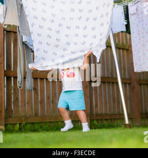 3 Jahre altes Kind versteckt sich hinter der Decke auf die Wäscheleine im Garten Stockfoto