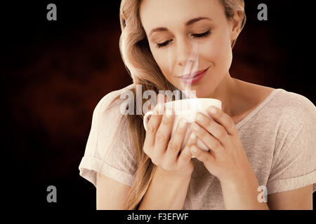 Zusammengesetztes Bild der lächelnde Blondine mit heißen Getränk entspannen Stockfoto