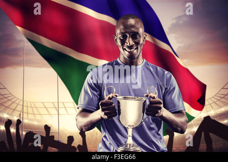 Zusammengesetztes Bild des Porträts von happy Athlet holding trophy Stockfoto