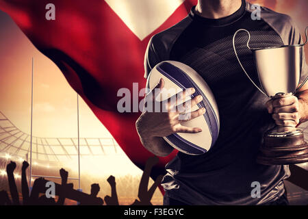 Zusammengesetztes Bild des Mittelteils des erfolgreicher Rugbyspieler holding, Pokal und ball Stockfoto