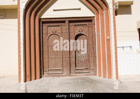 Reich verzierte Holztür in Adobe Gebäude in einer Stadt in das Sultanat Oman, eine sichere, freundliche Golfstaat Urlaubsziel Stockfoto