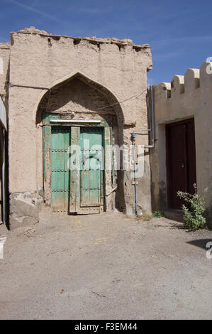 Reich verzierte Holztür in zerstörten Adobe Gebäude in einer Stadt in das Sultanat Oman, eine sichere, freundliche Golfstaat Urlaubsziel Stockfoto