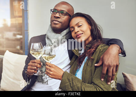 Glückseligen romantisch junge afrikanische zu zweit entspannen im jeweils anderen Arme und genießen Sie einen Schluck Weißwein auf einem Tisch im restaurant Stockfoto