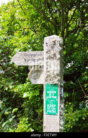 Eine Flechte verkrusteten zweisprachige Fußweg Schild am West Angle Bay in Pembrokeshire Coast National Park, Wales, Großbritannien Stockfoto