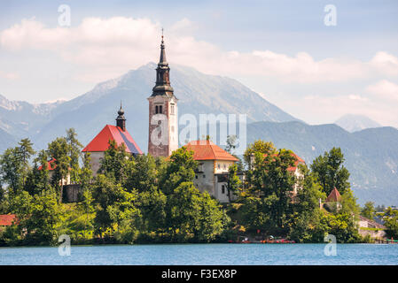 Kleine Insel mit römisch-katholische Kirche über Bled See, Slowenien mit Bergen im Hintergrund Stockfoto