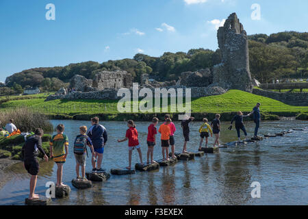 Reiter, überqueren den Fluss Ogmore mit Ogmore Burg, South Glamorgan, South Wales, UK Stockfoto