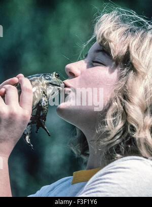 Ein junges Mädchen küsst ihr Frosch während ein Frosch springt Wettbewerb in Del Mar, Kalifornien, USA. Der gelegentliche Brauch, einen Frosch küssen bezieht sich auf ein Märchen über eine Prinzessin, die einen Frosch küsst und verwandelt die Amphibien in einen schönen Prinzen-- und sie leben glücklich bis ans Ende. Frosch Springturniere sind jährliche Veranstaltungen in einer Reihe von amerikanischen Gemeinschaften, einschließlich Calaveras County, Kalifornien, wo ein Frosch-Jubiläum seit 1928 stattgefunden hat. Der Wettbewerb entstand, nachdem amerikanische Schriftsteller Mark Twain (geb. Samuel Clemens) schrieb eine Kurzgeschichte "The feierte Jumping Frog von Calaveras County." Stockfoto