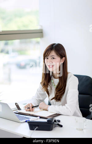 Porträt der schönen glücklich Geschäftsfrau sitzen am Schreibtisch Stockfoto