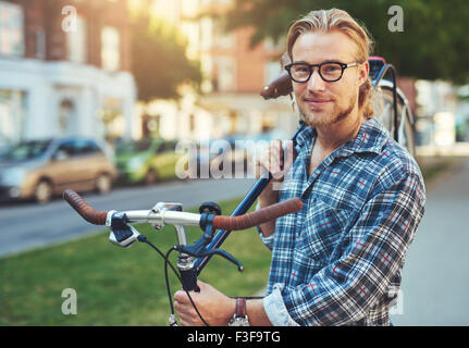 Porträt von blonden weißen Mann in der Stadt mit dem Fahrrad Stockfoto