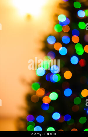 Eine helle multicolor Bokeh erstellt durch eine Reihe von de-fokussierte Licht auf einer Hälfte eines Weihnachtsbaumes. Stockfoto