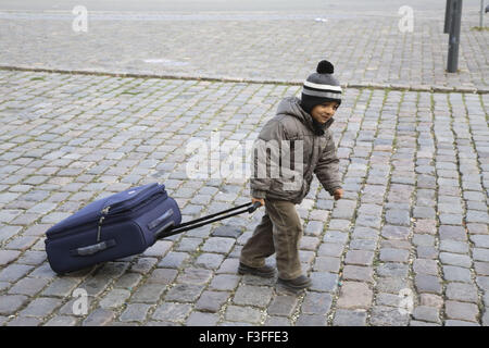 Kleinen vier Jahre alter Junge ziehen dunkle blaue farbige Gepäck-Trolley-Tasche tragen Winterkleidung MR3468 Stockfoto