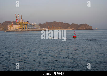 Kreuzfahrt-Schiff und Fischerboot im Hafen von Muscat in das Sultanat Oman mit Bergen im Hintergrund und eine rote Boje Stockfoto