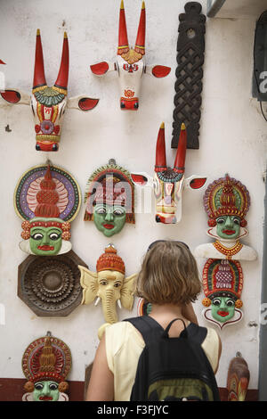 Touristen auf der Suche verschiedene Arten von Masken auf Wand lang angezeigt auf Mattancherry und Jude Street in Fort Kochi Kerala zu verkaufen Stockfoto