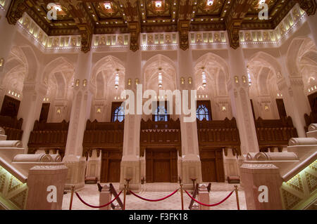 Lobby und Treppe mit hohen Bögen und eine reich verzierte Holzdecke im Royal Opera House in Shati Al-Qurm, Muscat, Oman Stockfoto