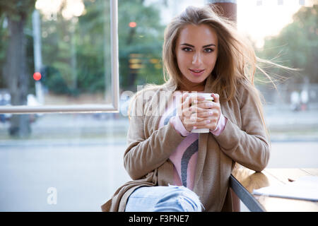 Porträt von einem glücklichen Mädchen trinken Kaffee im Café und Blick in die Kamera Stockfoto