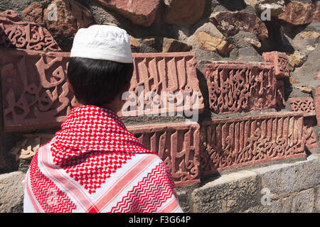 Muslimische Jungen beobachten Islamische Ornamentik des Quran Inschrift geschnitzt Qutab Minar Komplex aus rotem Sandstein Indo maurischer Kunst Delhi Stockfoto