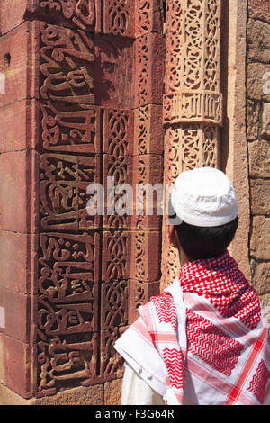 Muslimische Jungen beobachten Islamische Ornamentik Koran Inschrift geschnitzt Qutab Minar Komplex aus rotem Sandstein Turm Indo-muslimischen Delhi Stockfoto