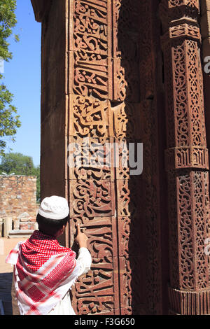 Muslimische Jungen beobachten Islamische Ornamentik Koran Inschrift geschnitzt Qutab Minar Komplex aus rotem Sandstein Turm Indo-muslimischen Delhi Stockfoto