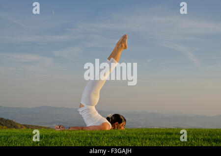 Junge Frau praktizieren Hatha-yoga Outdoor, zeigt die shalabhasana darstellen, locust