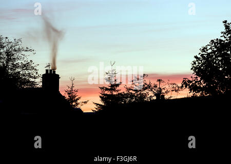 Rauch aus einem Schornstein Haus bei Sonnenuntergang, UK Stockfoto