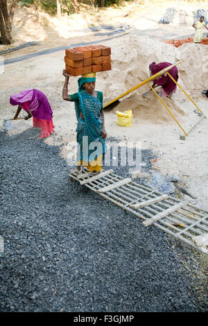 Eine Frau, die Ziegel auf dem Kopf auf einer Baustelle in Ahmedabad; Gujarat; Indien Stockfoto