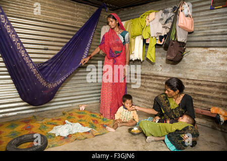 Arbeitende Mutter auf einer Baustelle, kurze Pause zu füttern und beruhigen Kinder; Ahmedabad; Gujarat; Indien Stockfoto