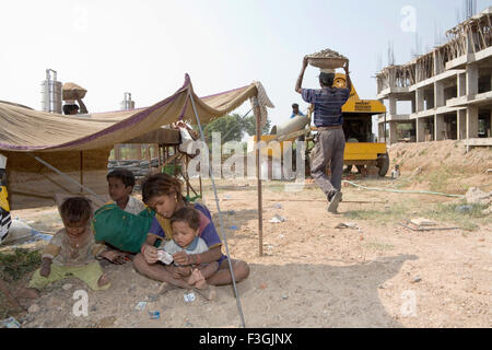 Kinder von Bauarbeitern spielen unter einem temporären Schutz während ihrer Eltern Ahmedabad Stockfoto