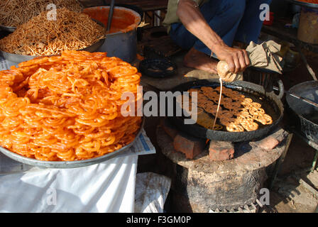 Menschen drücken Tuch Jalebi Teig im Topf zum Braten Stockfoto