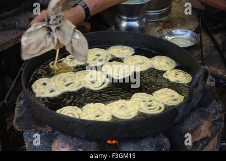 Menschen drücken Tuch Jalebi Teig im Topf zum Braten Stockfoto