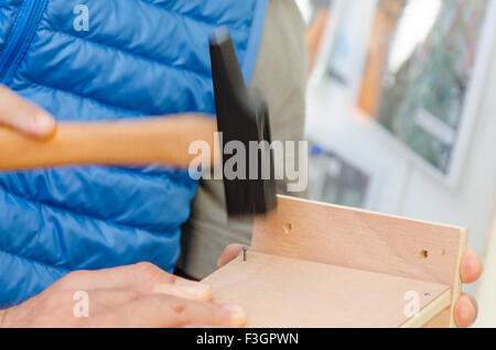 Hammer und Nägel durch Hände halten Stockfoto