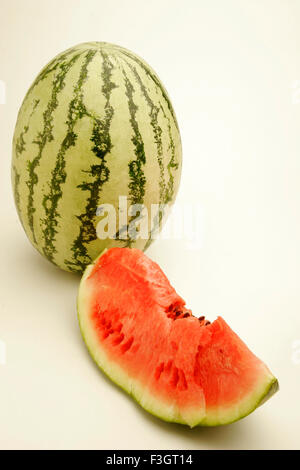 Früchte eine vollständige Wassermelone leichte dunkelgrünen Streifen eine geschnittene Scheibe zeigen rote wässrige Fruchtfleisch schwarze Samen Pune Maharashtra Stockfoto