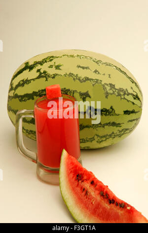 Früchte-Wassermelone Licht dunkelgrünen Streifen eine geschnittene Scheibe zeigen rote wässrige Fruchtfleisch schwarzen Samen Glas Melonensaft Pune Maharashtra Stockfoto