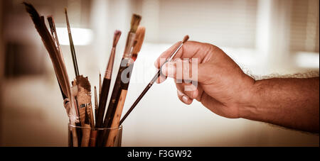 Des Malers Hand unter einer Bürste in einem Topf Stockfoto